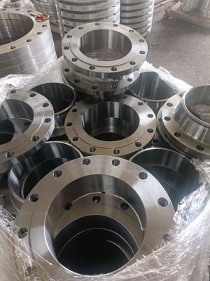 Flange di saldatura metalliche a collo ammucchiate (con collo, forate, metalliche) avvolte in plastica, accatastate in un magazzino industriale.