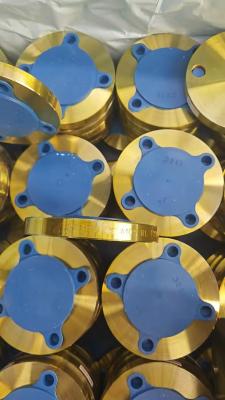 Đây là những mặt bích mù công nghiệp mạ vàng, xếp thành từng mẻ. Mỗi mặt bích được phủ một nắp bảo vệ màu xanh lam và có thể nhìn thấy các dấu hiệu (như "A105" & thông số kích thước) trên bề mặt. Đó là phụ kiện bịt kín đường ống cho các hệ thống công nghiệp