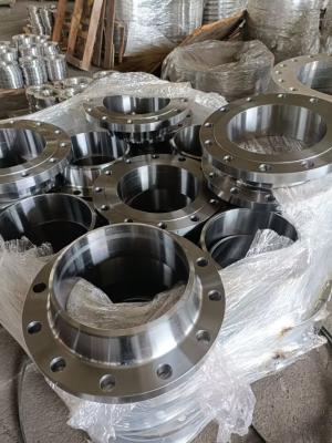 Flange di saldatura metalliche a collo ammucchiate (con collo, forate, metalliche) avvolte in plastica, accatastate in un magazzino industriale.